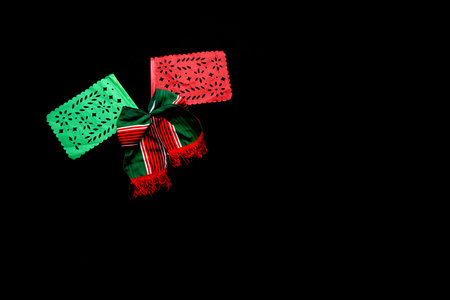 Decorative objects of Mexican party: pennants, green, white and red tricolor tie to celebrate Independence Day, Revolution and Day of the Dead in Mexico on a black backgroundの写真素材