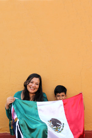 Latin Mexican mom and son show the flag of Mexico very proud of their culture and tradition, to...