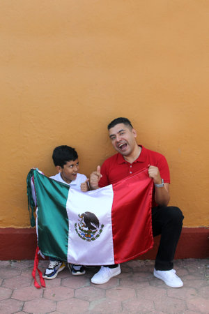 Latin Mexican dad and son show the flag of Mexico very proud of their culture and tradition, to celebrate the national holidays of Independence in September, Revolutionの写真素材