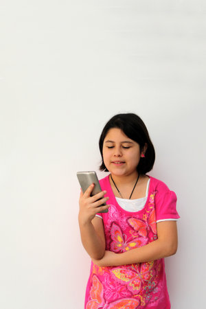 10-year-old Hispanic girl uses her cell phone to make video calls, play video games, send messages,...