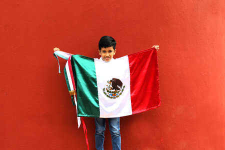 Latin Mexican boy of 8 years shows the flag of Mexico proud of his culture and tradition celebrates the national holidays of September 15 and Cinco de Mayoの写真素材