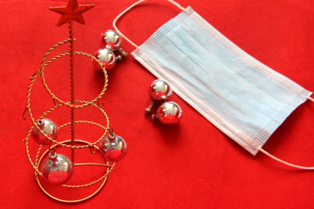 silver christmas star and spheres with protection mask on red background, christmas new normal covid-19の写真素材