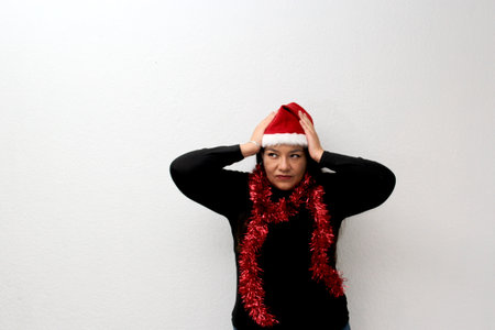 Latin adult woman with Christmas garland and hat angry, stressed, distraught about the arrival of...