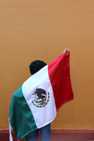 Latin Mexican boy of 8 years shows the flag of Mexico proud of his culture and tradition celebrates the national holidays of September 15 and Cinco de Mayoの写真素材