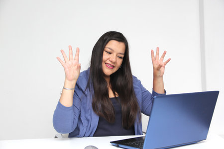 Latino adult woman speaks Mexican sign language with a deaf person through a laptop in a video call