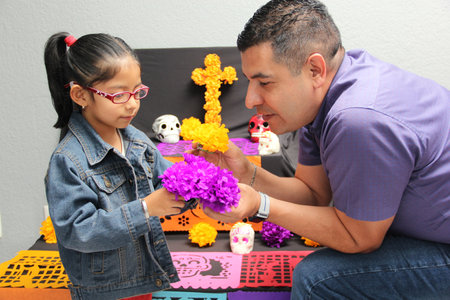 Mexican dad and daughter put the altar and offering of the Day of the Dead in their house for their deceased relatives part of the tradition and culture of Mexicoの写真素材