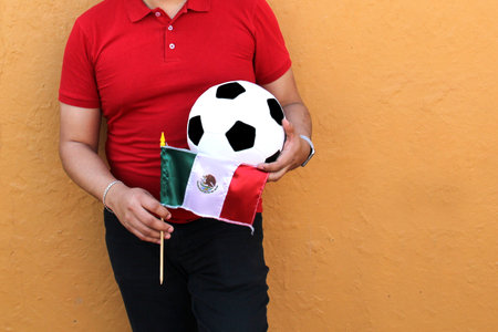 Mexican adult man plays with a soccer ball very excited that he is going to see the game with de mexican flag and wants to see his team winの写真素材