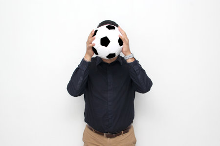 Latino adult office man plays with a soccer ball very excited that he is going to see the game and wants to see his team winの写真素材