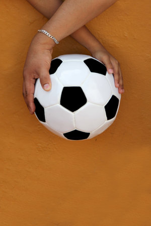 Latino dad and son share their love for soccer, they take a ball with their hands excited to watch...