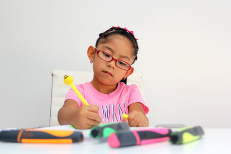 4-year-old brunette Latina girl with autism spectrum disorder ASD like Asperger, Rett and Heller draws at a desk, plays with colors alone antisocialの写真素材
