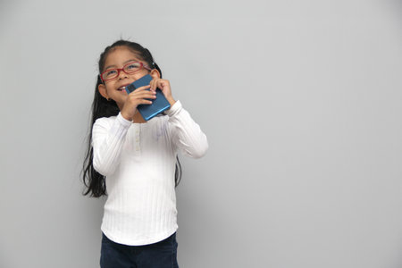 4-year-old latin girl uses her cell phone to make video calls, play video games, send messages, take photos, selfies, watch and record videos as an influencer and have funの写真素材