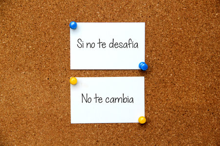 White note on cork board with message in Spanish language "If it doesn't challenge you, it doesn't change you"の写真素材