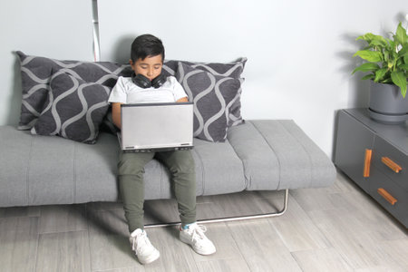9-year-old Hispanic boy plays video games on his laptop with headphones leading to being overweight...