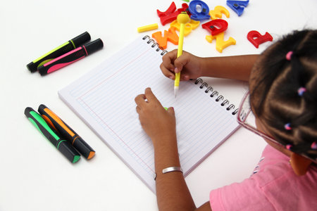 4-year-old brunette Latina girl with dysgraphia, writing ability disorder, difficulty or inability to write written texts with intellectual and neurological deficiency, learning and language disorderの写真素材
