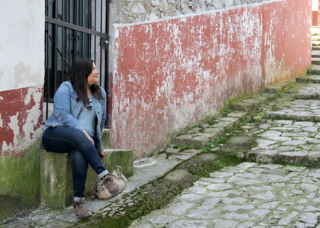 Black hair latin woman with protection mask tourist in the streets with view of wooden door and windowsの写真素材