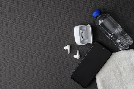 Mat to exercise with the necessary objects such as wireless headphones, cell phone, water to hydrate, sweat towel and locker keysの写真素材