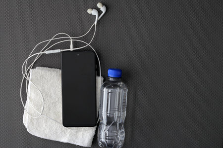 Mat to exercise with the necessary objects such as wireless headphones, cell phone, water to hydrate, sweat towel and locker keysの写真素材