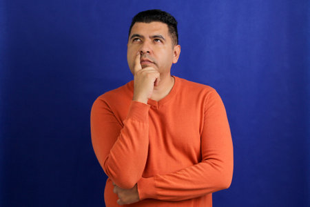 Adult dark-skinned Latino man in his forties appears pensive and thoughtfulの写真素材