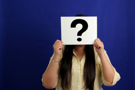 Latino adult woman shows a question mark, wonders, doubts, suspects, assumes, fears and distrustsの写真素材