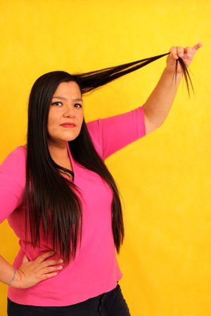 Latin adult woman with very long straight hair suffers and is sad because her hair is a mess and is very damaged with split endsの写真素材