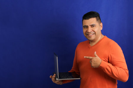 Dark-haired latino adult man uses laptop for work, online shopping, dating in apps looks excited and...