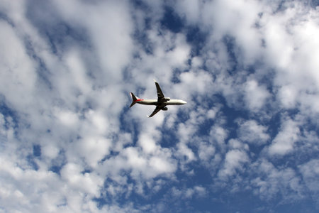 Airplane flying in the blue sky among the cloudsの写真素材