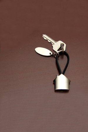Silver key ring in the shape of a house with the key to a new home recently bought in real estate to...