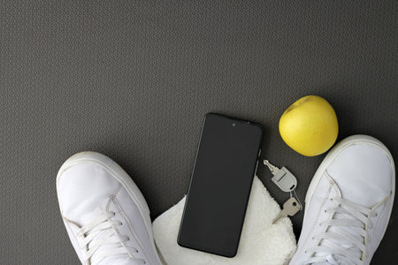 Objects to exercise on a mat with cell phone, apple, bottle of water, headphones, tennis towel and watchの写真素材