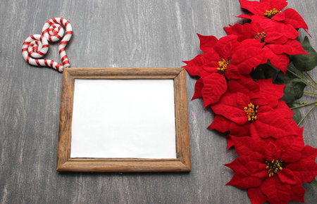 Photo frame surrounded by poinsettia flowers, canes and pinwheels as a Christmas prayer for a Christmas messageの写真素材