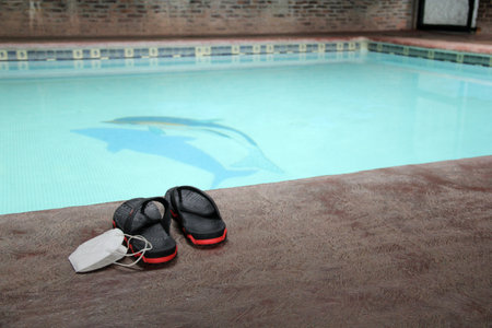 Pool to play on vacation next to flip-flops and an inflatable unicorn with face masks for the new normal of the Covid-19 pandemicの写真素材