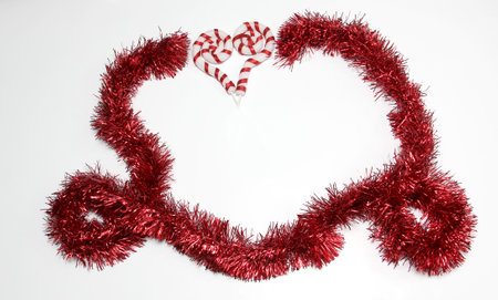 Bright red garland to frame Christmas message along with Mexican poinsettia flowers, handmade doll, canes and stars to celebrate Christmasの写真素材