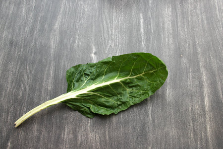 Green vegetables like parsley, celery, nopales, cucumbers, chard and spinach on a wooden table and...