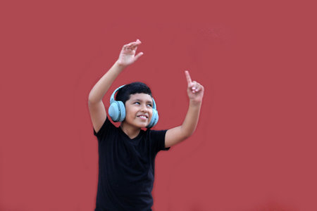 9-year-old dark-skinned Latino boy listens to his headphones and enjoys the music while dancing excited and happyの写真素材