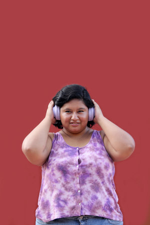 Young Latin woman of 20 years old fat brunette listens to music, podcasts and audiobooks with her headphonesの写真素材