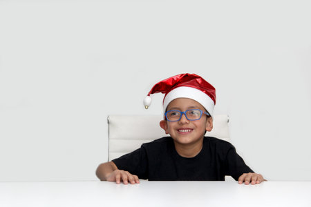 6 year old dark latino boy with eye glasses is ready to celebrate the holidays and write his letter...
