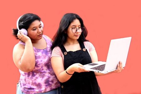 Young brunette latina student women use headphones and laptop to watch videos, social networks and...
