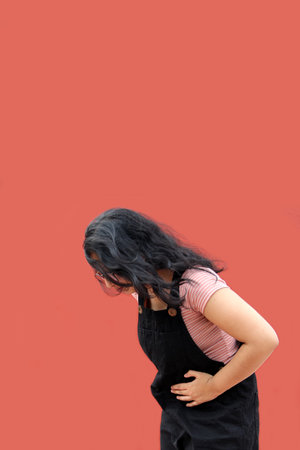 Teenage woman with early pregnancy appears sad, worried and in pain living in poverty and without...