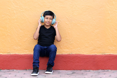 Brown Latino 9 year old boy with anti noise headphones for children with asperger syndrome, autism spectrum disorder, ADHD and children with sensitivity to loud noisesの写真素材
