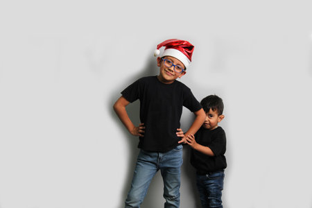 Dark-skinned Latino children, older brother in Santa hat takes care of his younger brother and spends quality time at the holidays to celebrate Christmasの写真素材