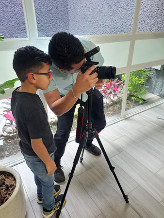 Dark-skinned Latino dad teaches his 7-year-old son to use the camera because he wants to work as a photographer when he grows upの写真素材