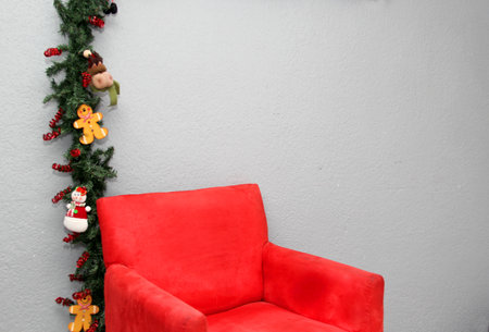 Red velvet armchair on gray background with frame of Christmas decorations like gingerbread cookie and snowmanの写真素材