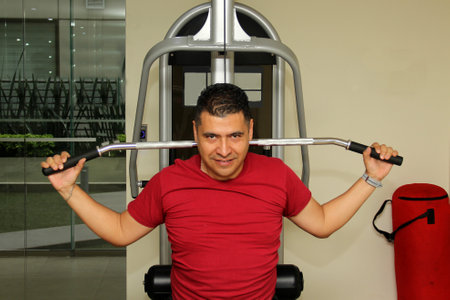 40-year-old dark-skinned Latino man does back and chest exercises as a New Year's resolution to...