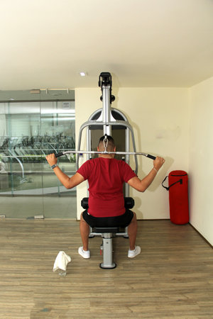 40-year-old dark-skinned Latin man does exercises to strengthen chest and back for rehabilitation...