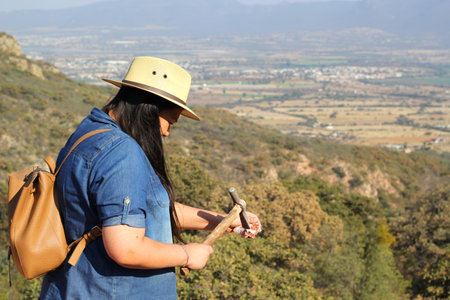 Latin adult woman geologist studies the details and characteristics of rocks, minerals and fossils in the mountainの写真素材