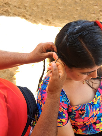 Woman combs her hair on the beach, pays to have braids made, a traditional tourist hairstyle in Acapulco Mexicoの写真素材