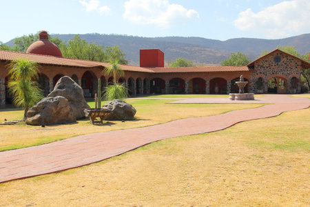 Colonnial farm and country house, stone and red brick construction with arches and green grass gardenの写真素材