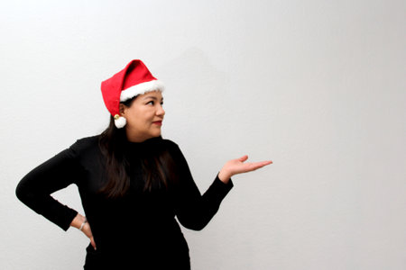 Latin adult woman with hat and Christmas garland shows her enthusiasm and happiness for celebrating Christmas and the new yearの写真素材