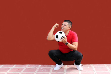 Latino adult man plays with a soccer ball very excited that he is going to see the World Cup and wants to see his team winの写真素材