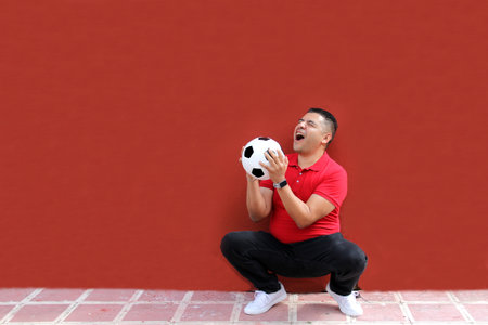 Latino adult man plays with a soccer ball very excited that he is going to see the World Cup and wants to see his team winの写真素材