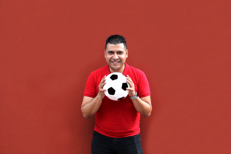 Latino adult man plays with a soccer ball very excited that he is going to see the World Cup and wants to see his team winの写真素材